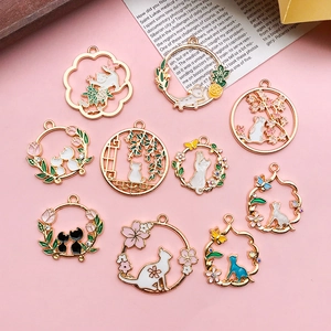 Detail view of ten gold alloy cat charms with colorful floral enamel for DIY jewelry