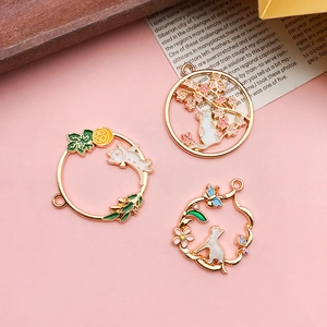 Detail of three floral cat DIY pendants with gold alloy and enamel finish charms
