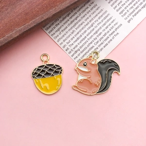 Detailed macro view of squirrel and acorn enamel charms with gold trim for DIY jewelry