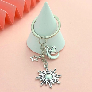 DIY sun moon and star silver keychain with heart crescent pendant on a pink background