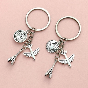 Travel keychain set with Eiffel Tower, globe and airplane pendants on pink background