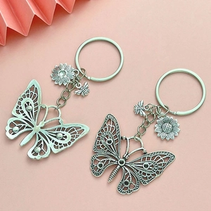 Detailed view of silver hollow butterfly keychains with sunflower and bee charms