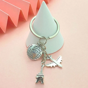 Travel themed keychain featuring Earth airplane and Eiffel Tower charms in vintage silver