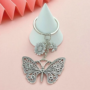 Vintage silver hollow butterfly keychain with sunflower and bee charms on a white stand