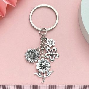 Silver alloy sunflower and daisy floral keychain set on pink textured background