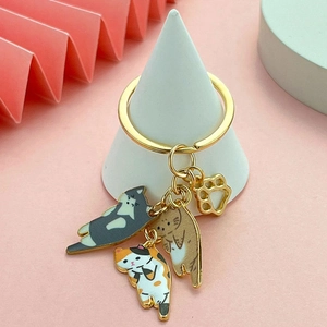 Cat theme keychain with enamel feline pendants and golden cat paw charm on white stand