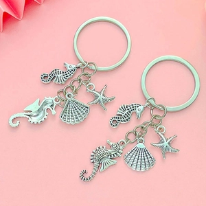 Ocean series keychain with silver starfish, shell, and seahorse charms on pink background