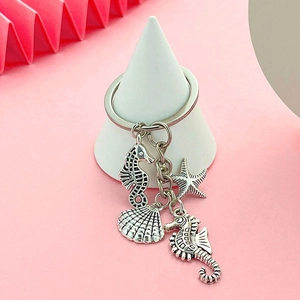 Silver marine keychain with sea horse, shell and starfish pendants on a modern pink background