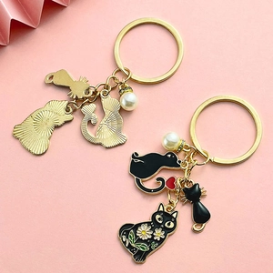 Porte-clés chat noir mignon avec finition dorée et charmes de marguerites émaillés
