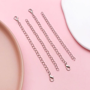 Macro shot of 4 silver jewelry extender chains with lobster clasps on a soft pink background