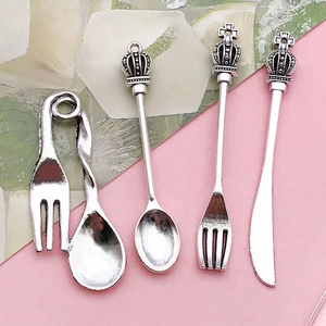 Set of four vintage silver alloy miniature cutlery pendants including knife fork and spoon