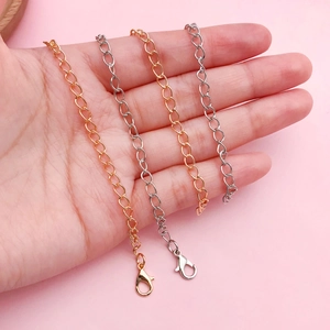 Hand holding assorted 10cm gold and silver necklace chains with lobster clasps