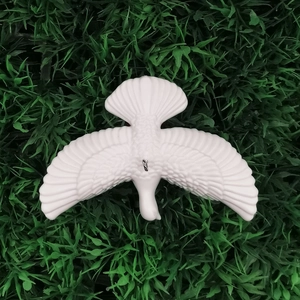 White decorative flying dove ornament with detailed feathers on green grass background
