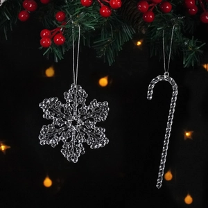 Close-up of transparent snowflake and candy cane ornaments with silver strings on pine branch