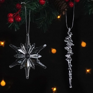 Clear snowflake and icicle crystal ornaments hanging on a festive Christmas tree branch