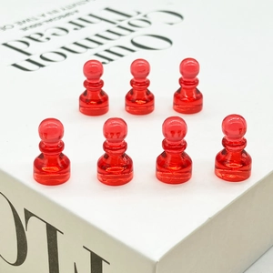 Close-up of seven red pawn-style magnetic push pins arranged on a decorative book