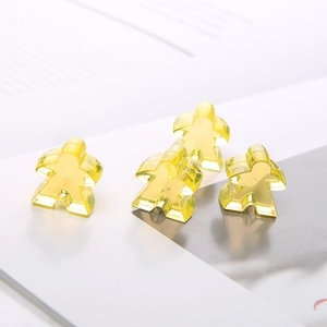 Detail view of four transparent yellow resin meeple game pieces on a white background
