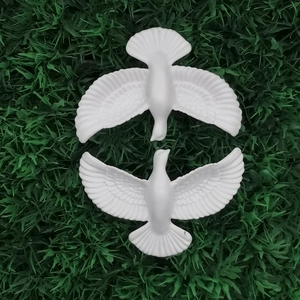 Two-piece set of white peace dove ornaments with feather details on green lawn background