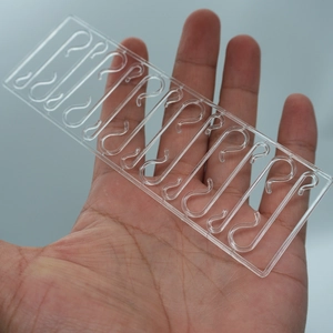 Close-up of 10 clear plastic S-hooks for Christmas ornaments held in a person's hand