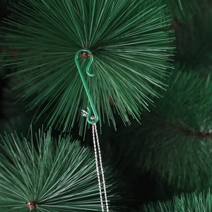 Detail of a green S-shaped plastic hook hanging from pine branches with a silver chain