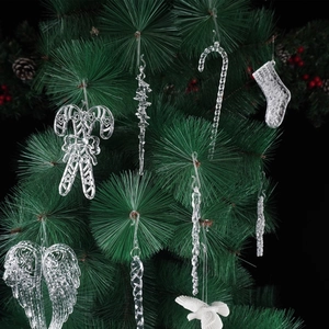 Close-up of translucent acrylic Christmas ornaments hanging on green pine tree branches