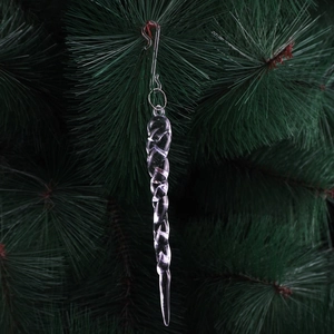 Transparent icicle Christmas ornament with spiral texture hanging on a green tree branch