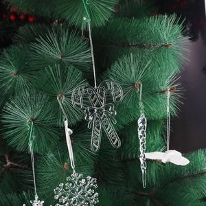 Clear acrylic snowflake and white bird ornaments set on a green Christmas tree branch