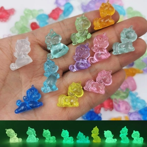 Glow-in-the-dark unicorn miniature resin figurines shown in hand for size comparison