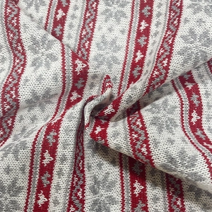 Detailed close-up of festive red and white Fair Isle knit fabric with snowflake patterns