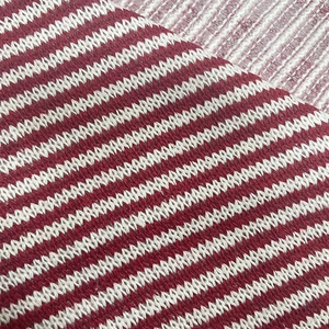 Close-up of soft red and white striped knitted fabric texture and fine fiber detail