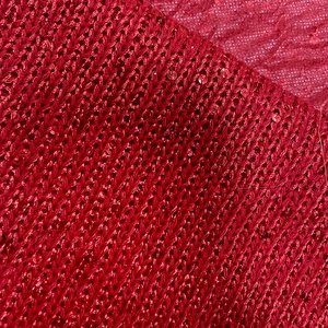 Macro shot of red knit fabric with shimmering sequins and intricate textile textures