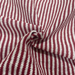 Detailed close-up of soft red and white striped knit fabric with crochet texture