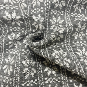 Macro shot of grey and white knitted snowflake patterns on soft jacquard fabric