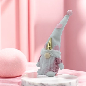 Pink unicorn gnome plush with sequins and heart hat on white marble stand