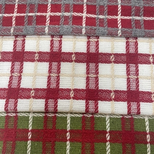 Red and green plaid knitted acrylic blend fabric samples stacked for Christmas decor