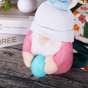 Detail of Easter gnome plush with pink burlap outfit holding a blue polka dot egg