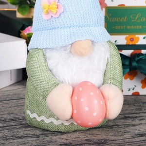 Handcrafted Easter gnome plush with blue knit hat and pink egg on wooden surface