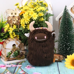 Detail of Highland Cow plush with long brown fur, pink flowers, and forest scene decor