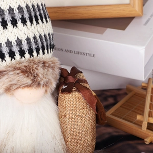 Detailed view of gnome plush doll with diamond knit hat and faux fur trim holding gift