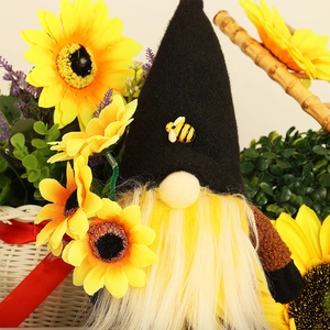 Gnome plush with bee theme and yellow beard sitting among sunflowers for harvest festival