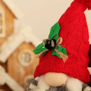 Detail of knitted red Christmas gnome hat with holly leaves and small metal bells