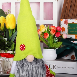Detail eines handgemachten Muttertags-Gnomes mit grünem Hut und rotem Herz vor Blumen