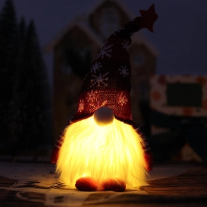 Close-up of a Christmas gnome with a red knitted snowflake hat and warm LED glowing lights