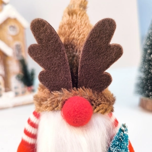 Détail d'un gnome de Noël avec des bois en peluche et un petit sapin enneigé
