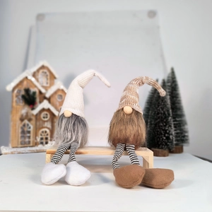 Detail of two Nordic Christmas gnomes with long legs sitting on a wooden bench decor