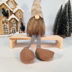 Detail of Christmas forest gnome with long legs and knitted hat on a wooden bench