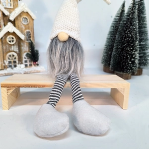 Close-up of a Christmas gnome with white knit hat and long grey beard on a wooden bench