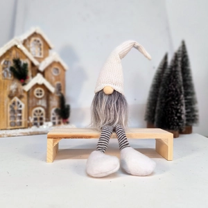 Detail of Christmas gnome with white knitted hat and striped legs on wooden bench