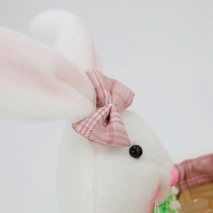 Detail eines weißen Plüsch-Osterhasen mit rosa Karo-Schleife und geflochtenem Süßigkeitenkorb