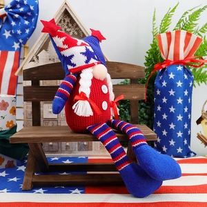 Detail of knit Independence Day gnome with star hat sitting on a rustic wooden bench